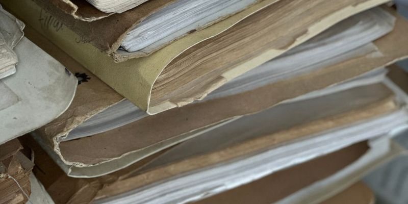 Stacks of old paper files in brown folders, representing lost and misplaced certificates