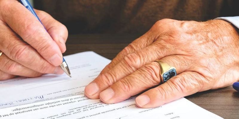 Close-up of a hand signing a document, representing name and signature mismatch cases