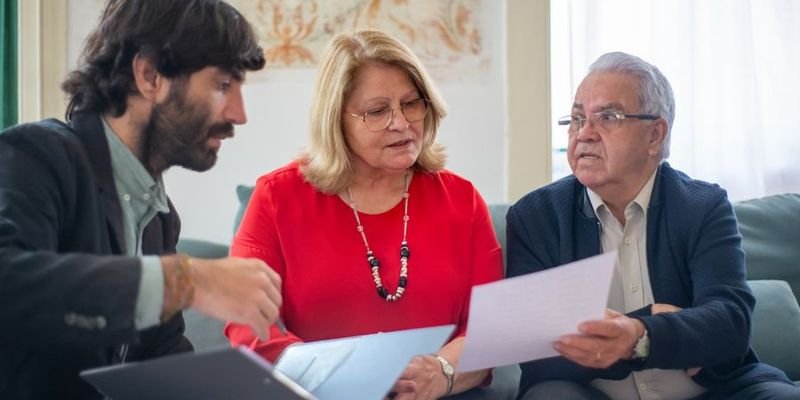 Adviser explaining documents to an elderly couple, representing transmission to legal heirs